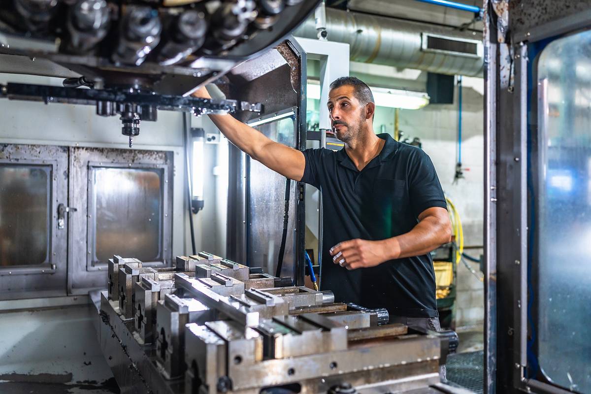 Ein Maschinenbediener überprüft das Werkzeugmagazin einer CNC-Fräsmaschine in einer Werkstatt.